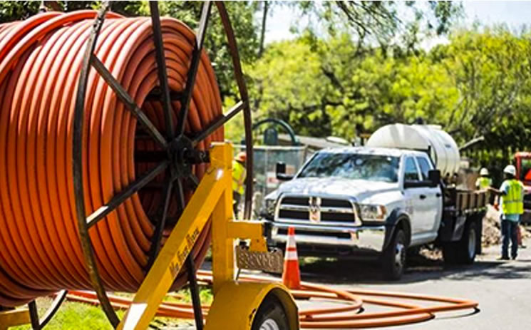 Fiber optic cable being laid by workers.
